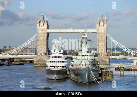 HMS Belfast und einer Luxusyacht vor Anker am Pool of London, Themse, Tower Bridge im Hintergrund Stockfoto