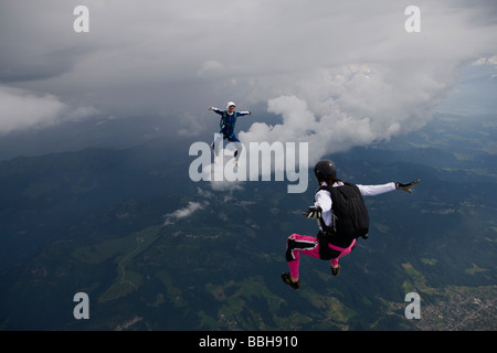 Fallschirmspringer sind innerhalb eines Teams in der Sit fliegen Position umeinander fliegen und Spaß über die Szenerie eine Wolke am Himmel. Stockfoto