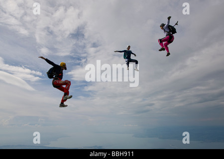 Fallschirmspringer sind innerhalb eines Teams in der Sit fliegen Position umeinander fliegen und Spaß über die Szenerie eine Wolke am Himmel. Stockfoto