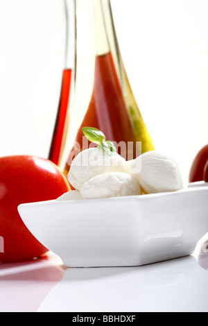 Mozzarellakugeln mit Basilikum in eine Schüssel geben Stockfoto