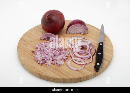Rote Zwiebeln (Allium Cepa), geschälte, gewürfelte Zwiebeln, in Ringe geschnittenen Zwiebeln auf einem Holzbrett mit einem Messer Stockfoto
