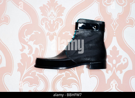 Mans schwarze Stiefelette erschossen vor einem rosa Herde Wallpaper Hintergrund Stockfoto