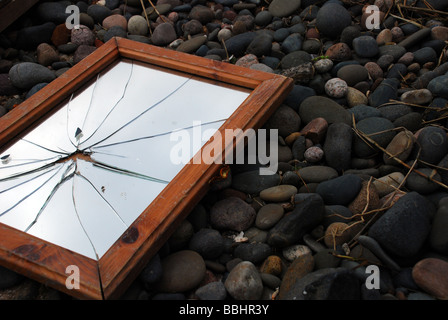 Zerbrochener Spiegel an einem steinigen Strand Stockfoto