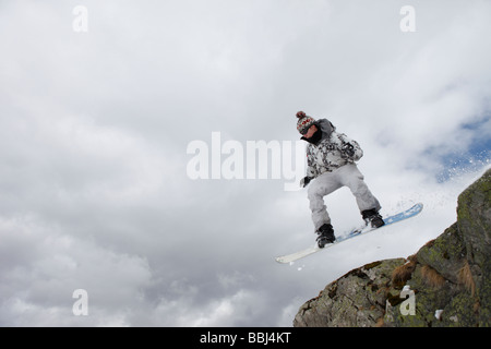 Snowboarder springt von einer Klippe in das Skigebiet Les Deux Alpen, Teil der Grande Galaxie Skigebiet, Alpen, Frankreich Stockfoto