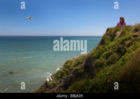 Junge Frau auf einer Klippe mit Blick auf Meer Stockfoto