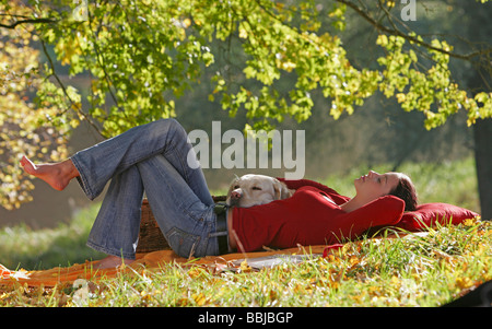 junge Frau mit Labrador Retriever Hund - liegend unter Baum Stockfoto