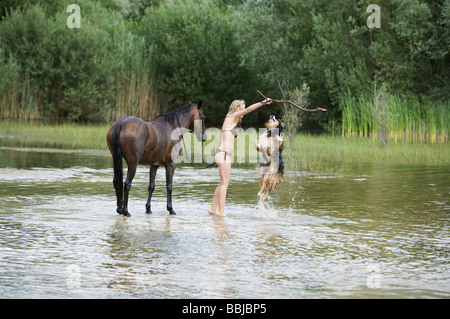 Mädchen mit Pferd und Australian Shepherd Hund im Wasser - spielen Stockfoto