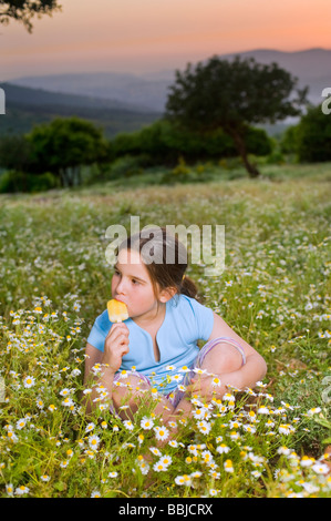 junges Mädchen mit einem Eis am Stiel in eine Blumenfeld bei Sonnenuntergang Stockfoto