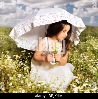 junges Mädchen im weißen Kleid mit Sonnenschirm in eine Blumenwiese Blumen pflücken Stockfoto