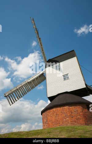 Alte hölzerne Windmühle auf roten Backsteinturm gegen blauen Himmel mit Wolken Mountnessing Stockfoto