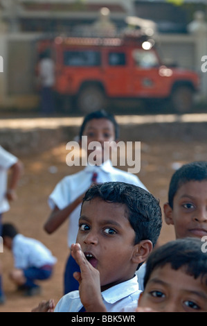 Schüler spielen im Hintergrund Landrover Defender, eine Entwicklungshelferin angehören. Indien, Kerala, Fort Cochin (Cochi, Kochi). Stockfoto