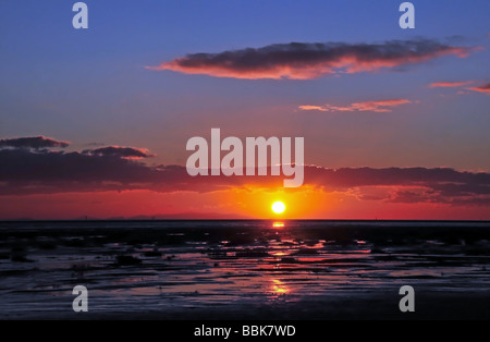 Die roten Wolken eines Sonnenuntergangs Winter abseits der Küste von North Wales, Süd-West über den Sand des Ribble Mündung, an Lytham, UK Stockfoto