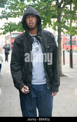 Porträt der Männer mit Kapuze auf, hält ein Mobiltelefon auf seine Hand und Blick in die Kamera, London UK 2009 Stockfoto