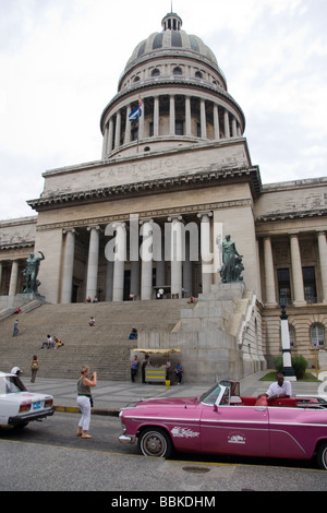 Leute sitzen auf den Stufen des nationalen Capitol Building Havanna Kuba mit rosa uns 50 s/60 s Auto außerhalb Stockfoto