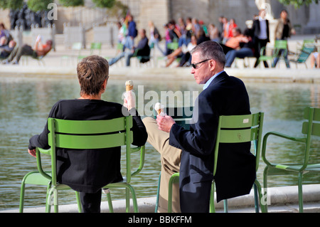 Ein Mann und eine Frau Eis essen sitzen auf einem Stuhl an Tuileries, Paris, Frankreich Stockfoto