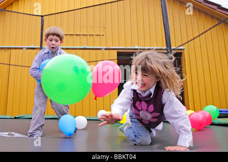 jungen und Mädchen spielen mit Luftballons auf einem Trampolin Stockfoto