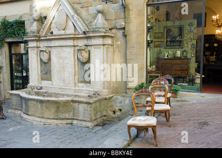 Antike Stühle aufgereiht auf der Straße vor dem Laden neben einer alten Wasch-Brunnen im Corso Italia Arezzo Stockfoto