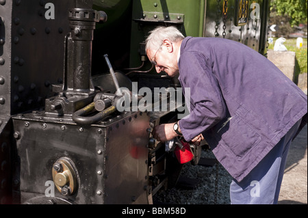 Volunteer Lokführer und Ingenieur schmiert Dampfmaschine mit Öl auf Schmalspur-Eisenbahnstrecke Touristenattraktion Stockfoto