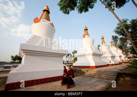 Mönche wandern vorbei an einer Reihe von Stupas An den Goldenen Tempel Bylakuppe Koorg Karnataka, Indien Stockfoto