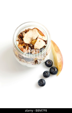 Müsli mit Joghurt in ein kleines Glas, Löffel Joghurt, Heidelbeeren, getrocknete Früchte, Apfel Stockfoto