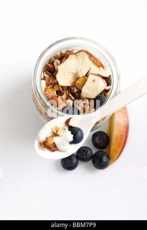 Müsli mit Joghurt in ein kleines Glas, Löffel Joghurt, Heidelbeeren, getrocknete Früchte, Apfel Stockfoto