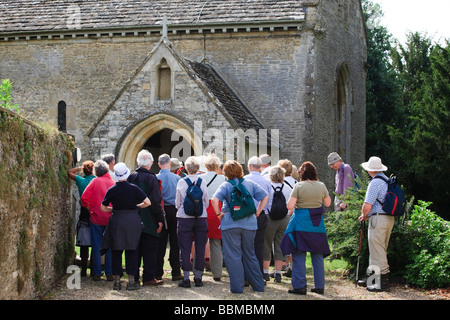 Eine Gruppe von Rentnern Blick auf eine historische Kirche in den Cotswolds, Eastleach Turville, Gloucestershire, Großbritannien Stockfoto