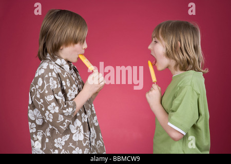 Zwei jungen mit Eis am Stiel vor einem roten Hintergrund Stockfoto