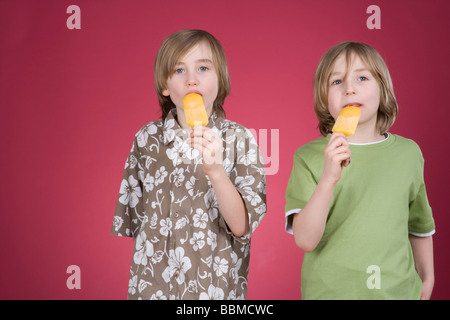 Zwei jungen mit Eis am Stiel vor einem roten Hintergrund Stockfoto