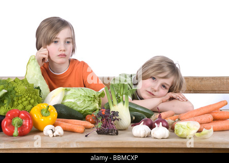 Zwei jungen an einem Tisch voller Gemüse, suchen verärgert Stockfoto