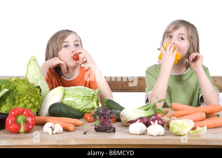 Zwei jungen an einem Tisch voller Gemüse, Naschen Stockfoto