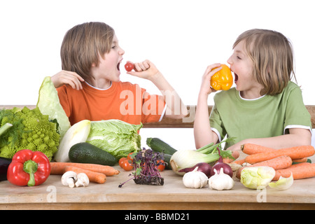 Zwei jungen an einem Tisch voller Gemüse, Naschen Stockfoto