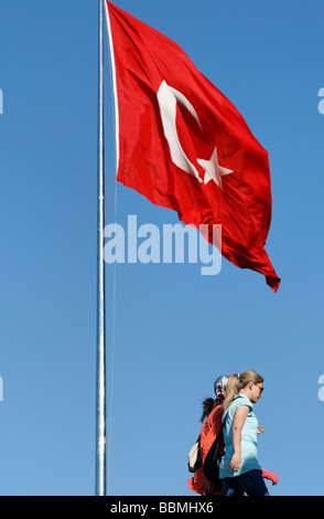 Junge Frauen in europäischen Kleidern zu Fuß unter der türkischen Flagge, Taksim-Platz, Beyoglu, Istanbul, Türkei Stockfoto