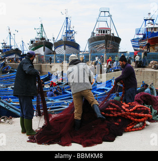 Fischer, am Hafen, die Befestigung der Netze. Meer gehen Fischereifahrzeuge im Dock, das Blau des Meeres spiegelt sich in der Farbe. Stockfoto