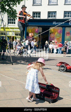 Ein junges Mädchen gibt Geld für eine Violinschule Seiltanz Straße Entertainer, Sidney Street, Cambridge, UK Stockfoto