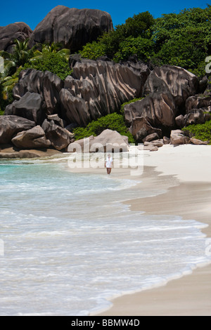 Frau rennt am Strand von Grand Anse, mit den typischen Granitfelsen von La Digue, Indischer Ozean, La Digue Island, Seychellen Stockfoto