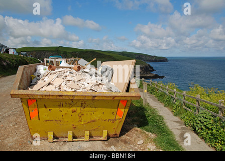 eine überspringen voller Bauherren Müll neben der Süd-West Küste Weg am port Isaac in Cornwall, Großbritannien Stockfoto