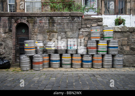 Bierfässer gestapelt gegen einer alten Mauer auf einer gepflasterten Straße Stockfoto