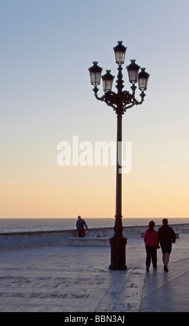 Laterne und Spaziergänger entlang der Strandpromenade in Cadiz, Andalusien, Spanien, Europa Stockfoto