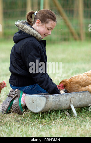 Mädchen, Fütterung der Hühner auf dem Bauernhof, Cheriton, Hampshire, UK. Stockfoto