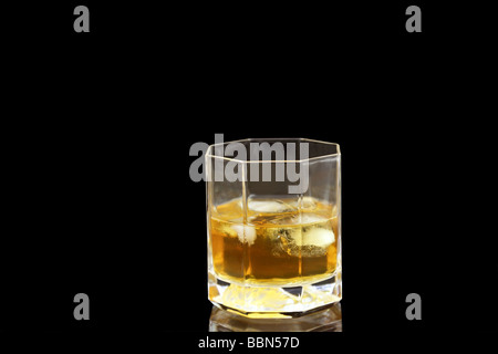 Kristall Glas halb gefüllt mit Whisky und Eis Stockfoto