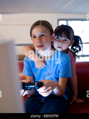 Eine Schülerin und ein Kindergarten Mädchen aufmerksam ein Videospiel spielen Stockfoto