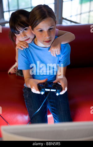 Eine Schülerin und ein Kindergarten Mädchen aufmerksam ein Videospiel spielen Stockfoto