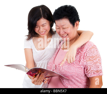 Ältere Frau und Tochter lesen auf ein Buch, mit Lächeln, auf weißem Hintergrund. Stockfoto