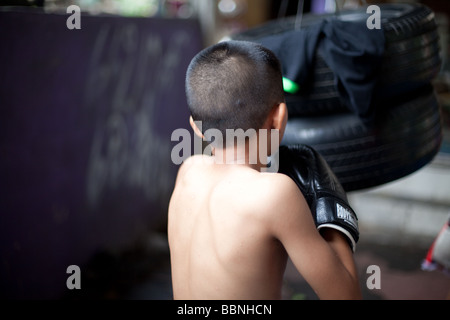 Junge skinny Muay thai Boxer Züge mit Reifen in einem Slum Camp leichte Bewegungsunschärfe mit Einfrieren flash Stockfoto