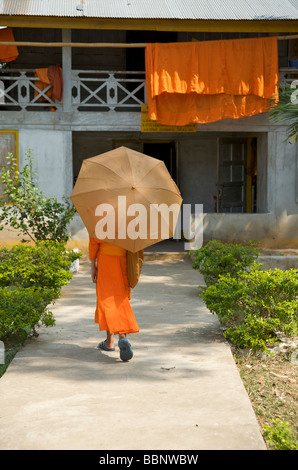 Ein buddhistischer Novize schützt sich vor der Sonne mit einem Regenschirm Stockfoto