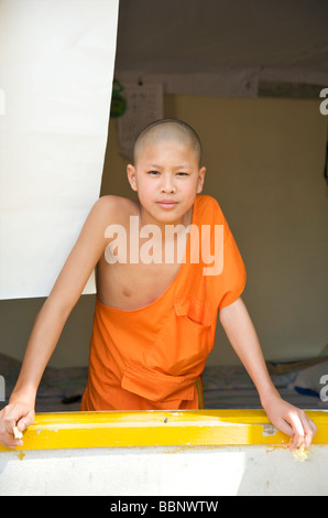 Eine junge Novizin buddhistische Mönche schaut aus dem Fenster in einem Tempel in Luang Prabang Stockfoto