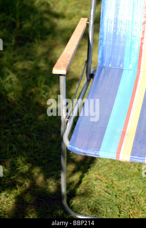 Retro 70er Jahre Liegestuhl auf einem überwucherten Rasen im Sommer Stockfoto