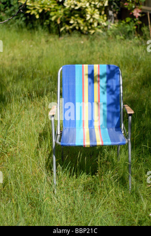 Retro 70er Jahre Liegestuhl auf einem überwucherten Rasen im Sommer Stockfoto