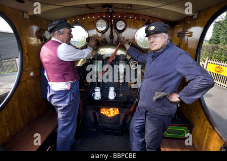 Ein Lokführer und Feuerwehrleute an der Bluebell Railway, eine erhaltene Bahnstrecke in Sussex, England. Stockfoto