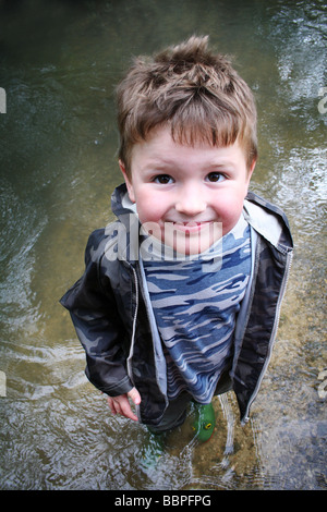 Nachschlagen im Stream tragen Gummistiefel stehen junge Stockfoto